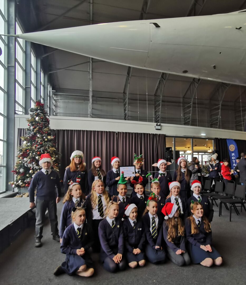 The Gorsey Bank choir stand proudly underneath Concorde at Manchester Airport