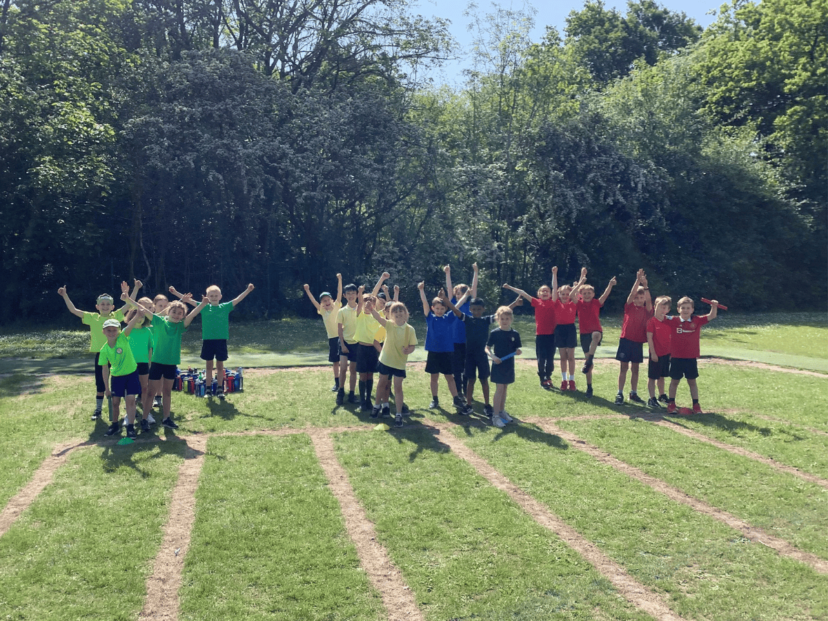 Year 3 Gorsey Bank pupils wear colourful House tshirts and stand on the sports track ready to compete in Sports Day.