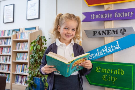 A Gorsey Bank pupil holding a book in the library.